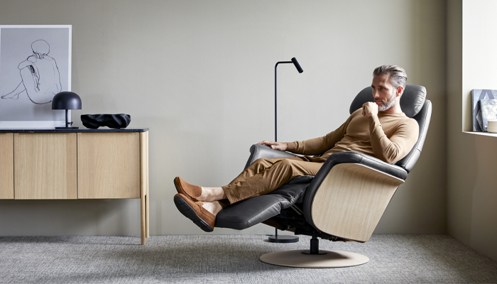 Stressless Sessel • Ein Mann sitzt mit überschlagenen Beinen auf einem schwarz, braunen Sessel • Meyerhoff Stressless Sessel • Ein Mann sitzt mit überschlagenen Beinen auf einem schwarz, braunen Sessel • Meyerhoff