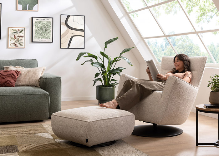 Frau sitzt auf beiges Sessel mit Hocker und liest • Sessel Lilaia Natura Home • Meyerhoff Frau sitzt auf beiges Sessel mit Hocker und liest • Sessel Lilaia Natura Home • Meyerhoff